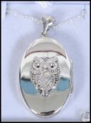 A silver lucky owl locket set to a silver fine linked chain.