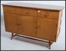 A retro 1950's Ercol elm sideboard being raised on tapered legs with two drawers over a cupboard