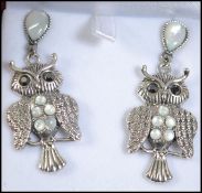 A pair of silver and moonstone adorned earrings in the form of a pair of owls.