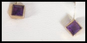 A pair of hallmarked 9ct gold and princess cut amethyst earrings. Hallmarked Birmingham.