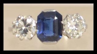 A platinum diamond and sapphire three stone ring set with a central emerald cut blue sapphire