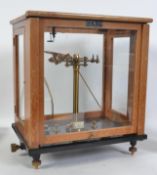 A pair of mid century wooden cased scientific scales in brass set to a black glass base with