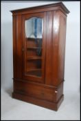 An Edwardian mahogany Arts & Crafts wardrobe having single mirror door over plinth drawer base.