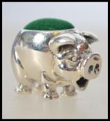 A pretty silver pin cushion in the form of a miniature pig having green baize cushion atop.