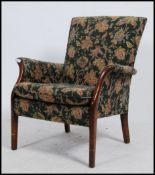A vintage mid century Parker Knoll armchair having a chintz upholstered fabric being raised on