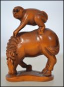 A carved wooden Japanese - asiatic netsuke in the form of a monkey on a horse.