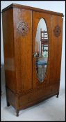 A 1920's oak mirror wardrobe having single door with plinth drawers base and flared cornice atop