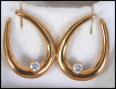 A pair of hallmarked 18ct gold and diamond earrings in the form of a horseshoe.