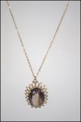 A hallmarked 9ct gold pendant necklace strung with a sunburst pendant set with a smokey quartz.