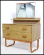 A 1960's faux teak wood dressing table chest of drawers having shaped mirror over chest and raised