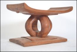 A 20th century African tribal stool having an angular seat raised on four carved supports on a