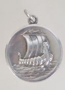 A 925 silver Georg Jensen circular silver pendant cast with Viking long boat.