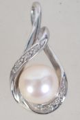 A hallmarked 9ct white gold diamond and peal pendant with crossover bale. Measures 2cms.