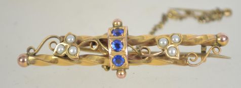 An Edwardian 9ct gold blue stone and pearl brooch with filigree scroll decoration having a c clasp