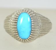 A silver white metal ladies dress ring set with turquoise style central stone.