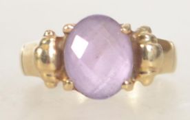 A hallmarked 9ct gold faceted amethyst ladies dress ring having scroll shoulders.