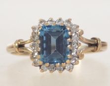 A hallmarked 9ct gold ladies dress ring with a large central blue stone and diamond surround.