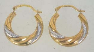 A pair of 9ct gold hoop earrings with textured white gold decoration. Marked 375. Tests 9ct gold.