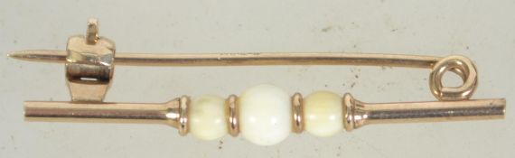 A early 20th century 9ct gold bar brooch with ivory ball styling with clip c clasp. Measures 3.3cms.