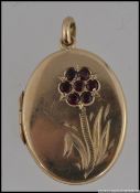 A hallmarked 9ct gold locket with flower decoration to front set with a cluster of garnets.