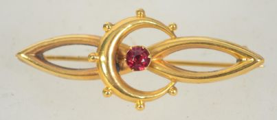 An early 20th century 9ct gold bar brooch with crescent moon and set red stone with C clasp.