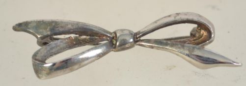 A silver brooch in the form of a bow with roller clip clasp. Marked Silver. Measures 2 1/4 inches.
