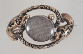 A Victorian 9ct rolled gold mourning brooch of scroll form with Champleve black enamelling,