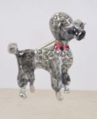 A vintage white metal enamel and marcasite figural brooch in the form of a poodle having a roller