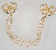 A 1960s double brooch with triple pendant chains and loop catch in goldtone metal. Measures 14.