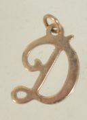 A 9ct gold pendant charm in the form of the letter D. Marked 9ct tests 9ct gold. Measures 1.5cms.