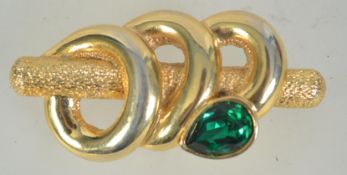 A large vintage abstract brooch of a snake coiled around a branch with green rhinestone head and