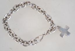 A heavy silver bracelet marked 925 with cross shaped heavy charm and lobster claw clasp.