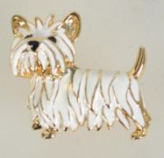 A vintage gold tone and enamel brooch in the form of a terrier dog with roller clip clasp.