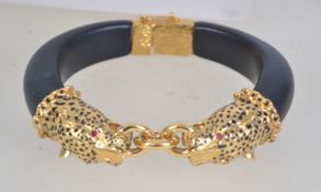 A vintage leopard head clamper bracelet with enamelled leopards heads with red glass eyes with