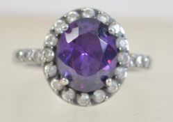 A 925 silver and CZ ring with central purple stone. Size Q.5. Marked 925 CZ.