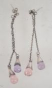 A pair of white metal drop earrings with post backs and pink and purple glass drops.