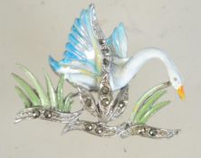 A vintage silver tone and enamel brooch in the form of a swan in flight with marcasite set reeds