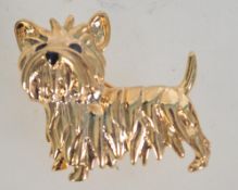 A vintage gold tone and enamel brooch in the form of a terrier dog with roller clip clasp.