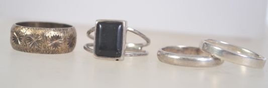 Four 925 silver rings to include onyx set ring with split shoulders and a star cut decoration band