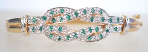 A gilt silver hinges bangle set with emeralds with box clasp. Weighs 25 grams measures 6.5cms.