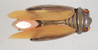A vintage cicada brooch having rhinestones a peach opalescent glass body and amber glass wings with
