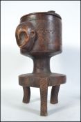 An unusual African tribal art foot pot on stand having figural face mask handles,