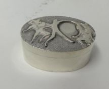A modern oval silver box by Eric West with relief figural decoration to the cover, (Eric West,