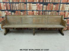 A substantial vintage oak pew with panelled back and bowed stretchers of peg jointed construction,