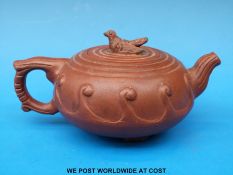 A Chinese Yi-Xing terracotta teapot with bird finial and raised on figural fish feet.