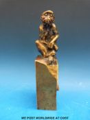 A bronze or brass figure of a monkey, naturistically modelled, seated on a pedestal,