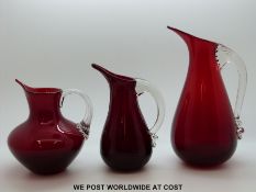 Three Whitefriars ruby glass jugs with applied celery handles, shape numbers 9419 and 9649,