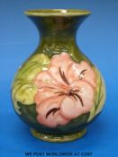 A Moorcroft pottery vase in Hibiscus pattern on a green ground (height 13cm)