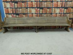 A substantial vintage oak pew with panelled back and bowed stretchers of peg jointed construction,
