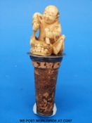 A Japanese ivory carving of a man making a mask in the form of a Shi Shi dog,